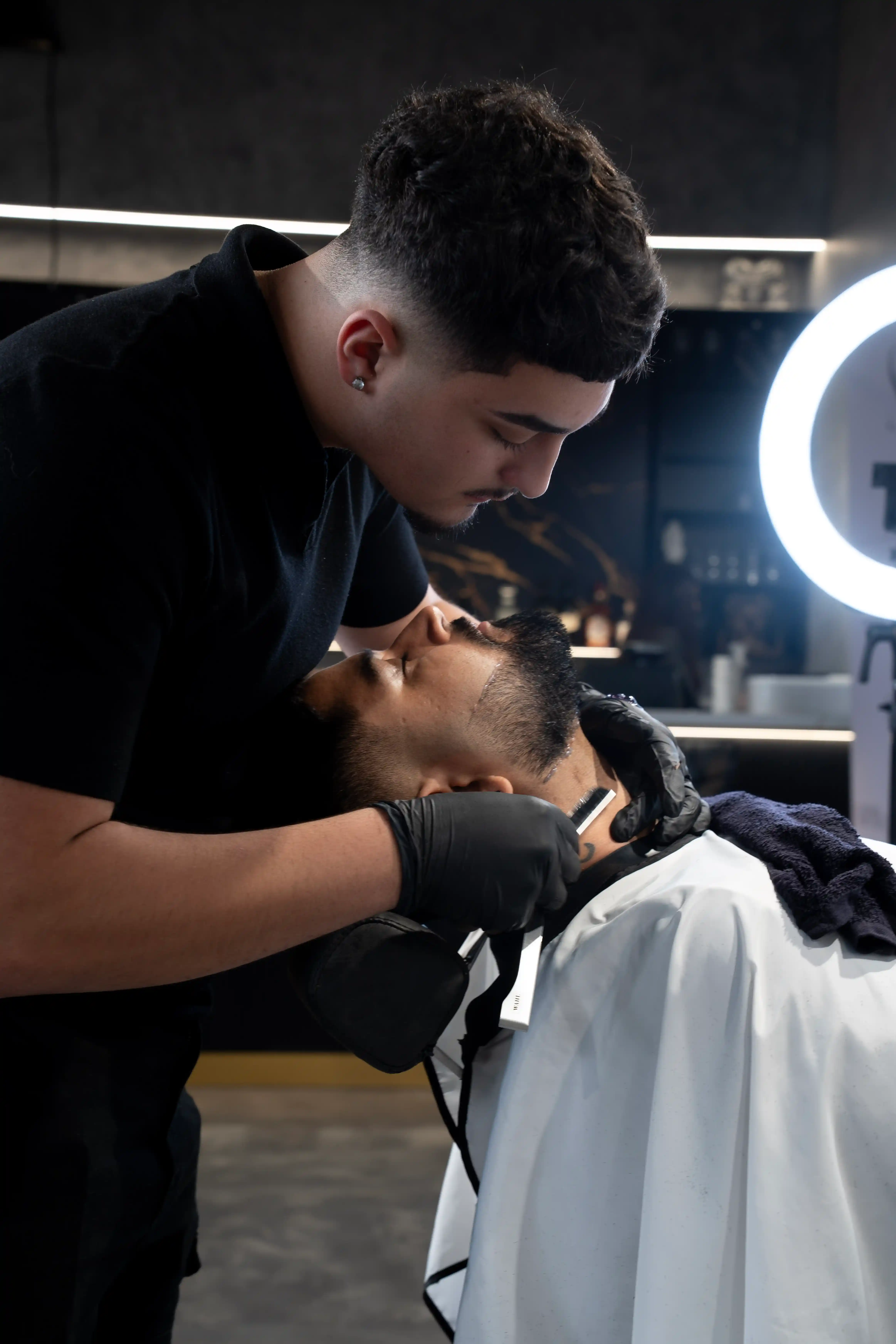 Senior barber John Doe expertly trimming a client's beard